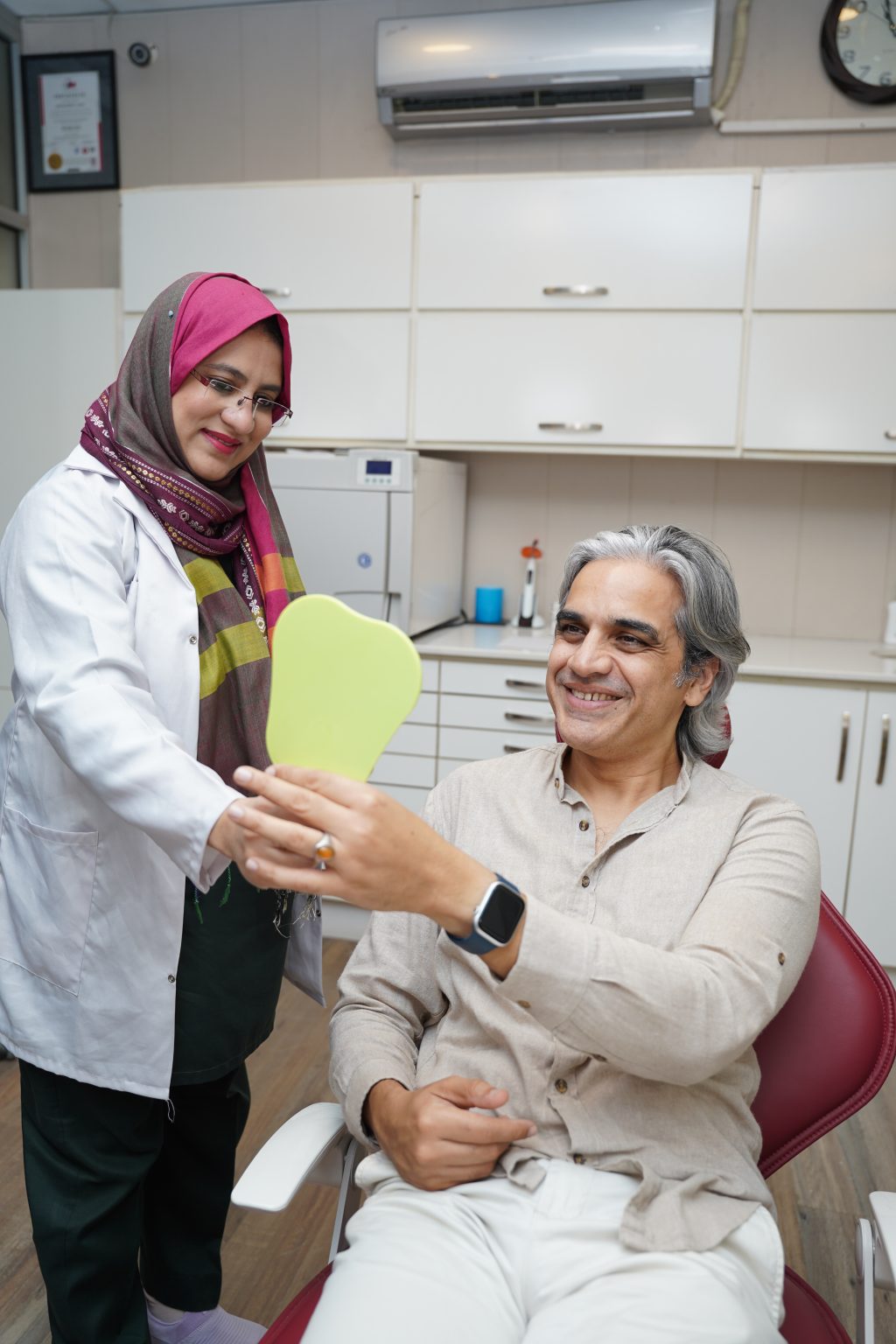 A TV artist, Omair Rana, sees his smile in the mirror at the dental clinic in Lahore..