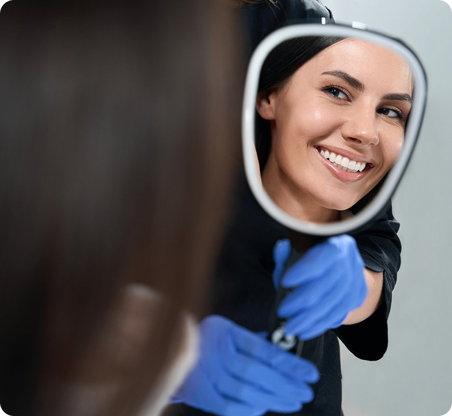 A patient sees her brighter smile in the mirror after getting teeth bleaching.